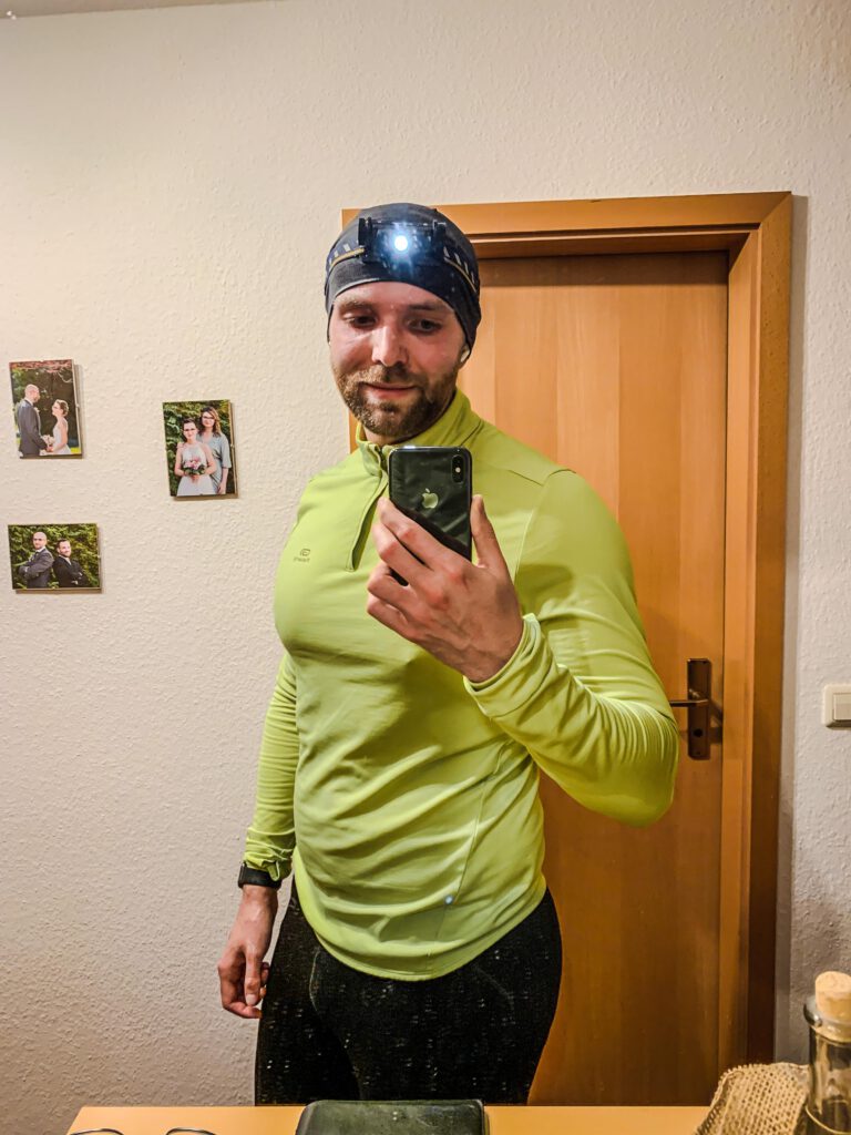Läufer im SPiegel-Selfie mit Stirnlampe und neongelbem Oberteil