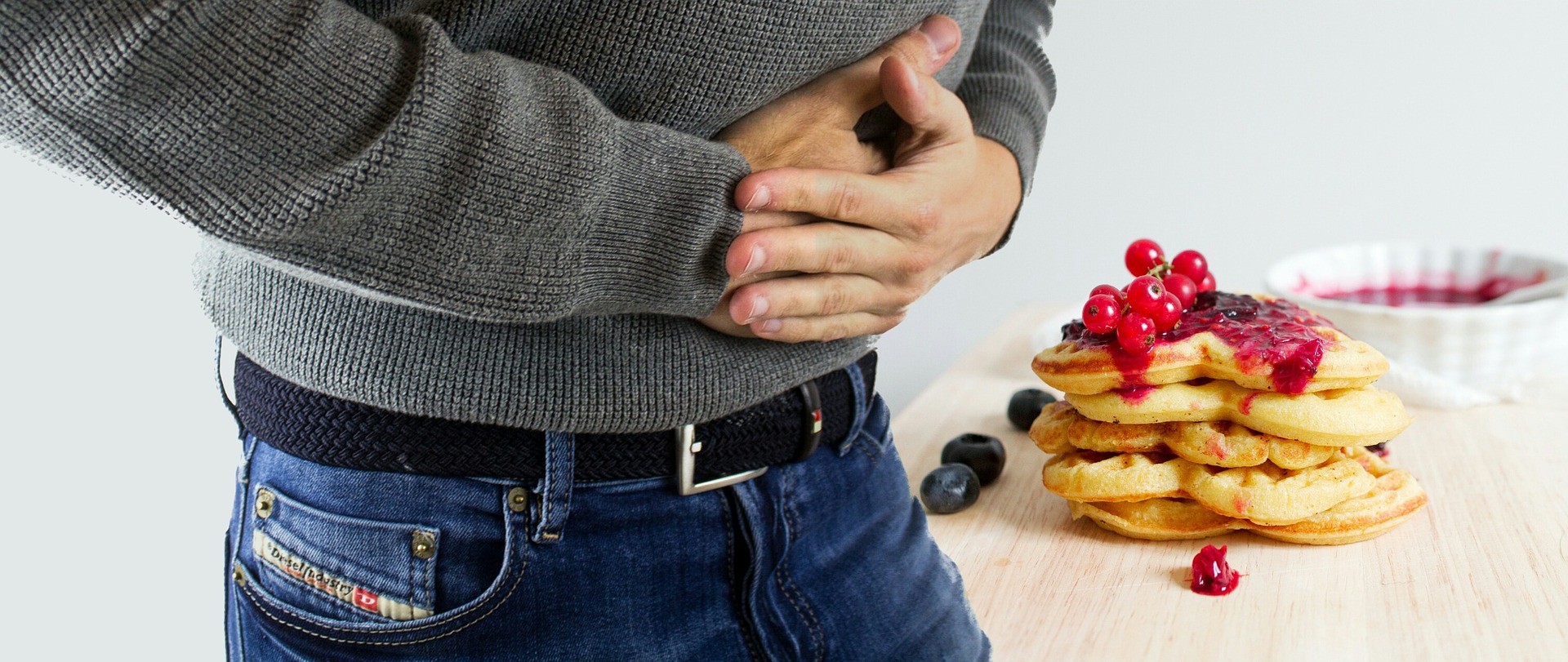 Mann hält den knurrenden Magen und steht nehmen einem Teller mit Pancakes