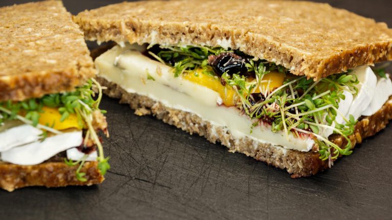 Halbgeteiltes Sandwich liegt auf einem dunklen Tisch